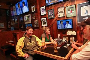 Sam's Place patrons laugh as they drink beer and watch a football game on their booth's personal TV