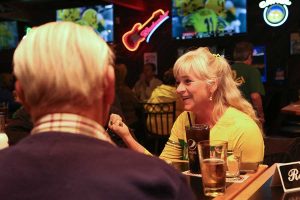 woman smiling and chatting with friends at Sam's Place Tavern in her Oregon Duck's gear