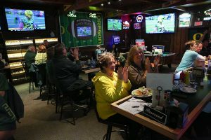 Sam's Place patrons clap for a play in an Oregon Ducks football game