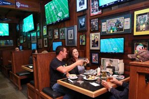 A couple enjoys a meal next while watching a football game at Sam's Place Tavern